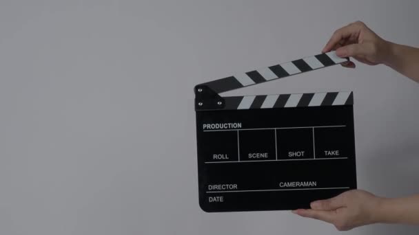 Movie slate or clapperboard hitting. Close up hand holding empty film slate and clapping it. Open and close film slate for video production. film production. color background studio. ready to shoot - Materiał filmowy, wideo