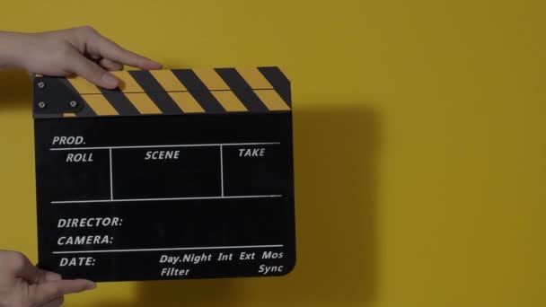Movie slate or clapperboard hitting. Close up hand holding empty film slate and clapping it. Open and close film slate for video production. film production. color background studio. ready to shoot - Felvétel, videó