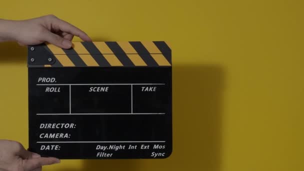 Movie slate or clapperboard hitting. Close up hand holding empty film slate and clapping it. Open and close film slate for video production. film production. color background studio. ready to shoot - Video