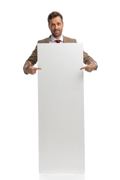 atractivo hombre de negocios apuntando a su tablero vacío y sintiéndose emocionado contra el fondo blanco - Foto, Imagen