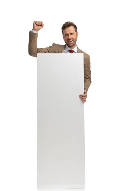 збуджений бізнесмен, який відзначає успіх і показує свою вертикальну порожню дошку на білому тлі
 - Фото, зображення