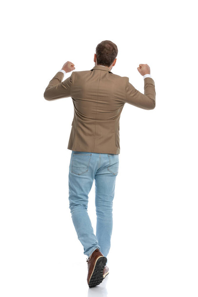rear view of a businessman walking away from the camera and celebrating success against white background - Foto, Imagen