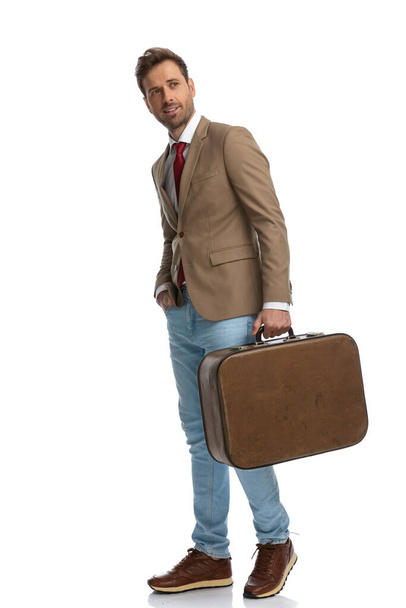 side view of an attractive businessman holding one hand in pocket and a briefcase in the other - Photo, Image