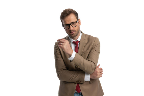 young businessman sensually folding his arms and wearing eyeglasses in a fashion pose - Foto, Bild