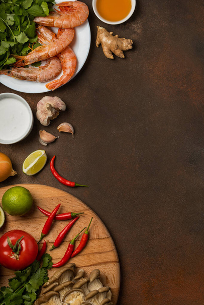 Fresh ingredients of tom yum soup on a tray and plate on a dark background, top view - Foto, Imagem