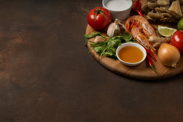 Fresh ingredients of tom yum soup on wooden tray on dark background - Photo, image