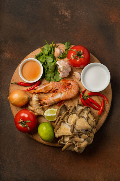 Fresh ingredients of tom yum soup on wooden tray on dark background - Photo, Image