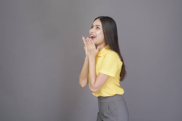 a young confident beautiful woman wearing yellow shirt is on grey background studio - Photo, Image