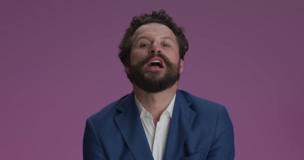 crazy happy man in suit standing with folded arms, screaming, having fun and grimacing, making crazy faces, being idiot on purple background - Video