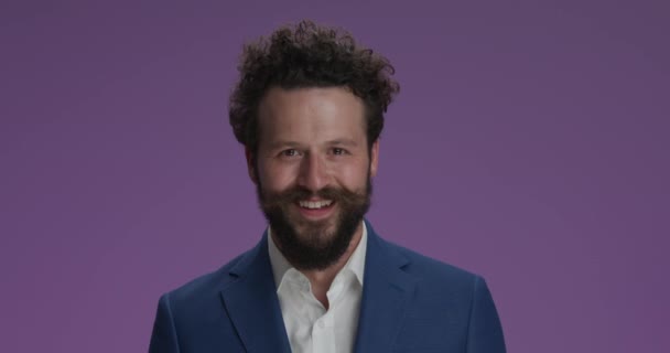happy young businessman in suit with beard and moustache, moving head both sides, laughing and having fun, sending kisses and being crazy on purple background - Πλάνα, βίντεο