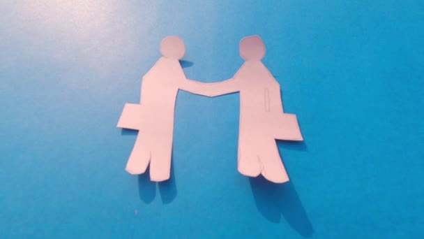 Dos hombres de negocios estrechando las manos sobre fondo azul. Diseño de negocios feliz. Origami Papel artesanal formas decorativas y figuras. - Imágenes, Vídeo