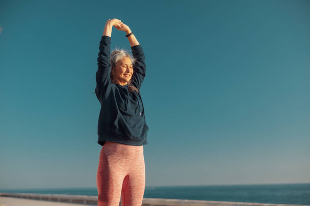 Uśmiechnięta kobieta aktywnie trenuje na nabrzeżu - Zdjęcie, obraz