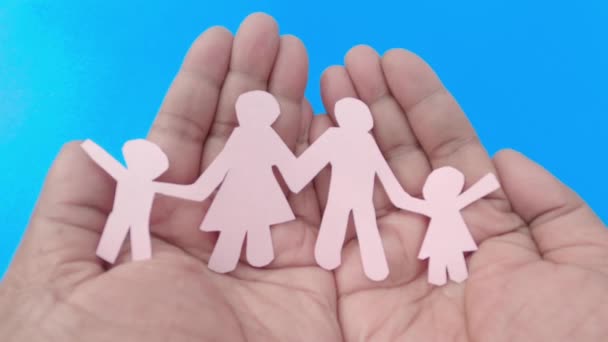 Famiglia felice carta su una mano uomo con il palmo rivolto verso l'alto sullo sfondo blu. Zoom in avanti. Origami Papercraft forme decorative e figure. - Filmati, video