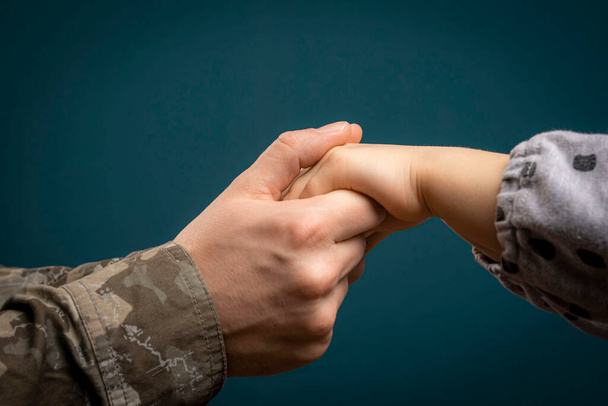 A soldier's hand holds a child's hand in close-up. My father is a military man. A soldier and a child. Father's love - Foto, Bild