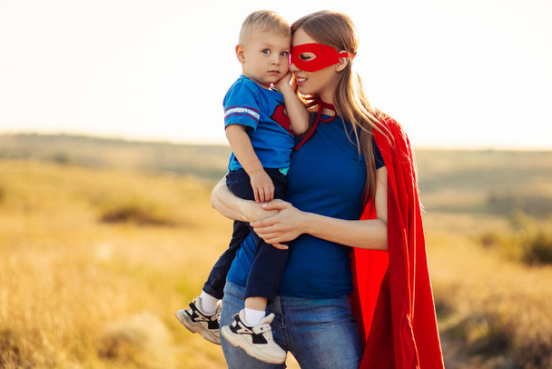 Happy loving family. Mom and her son are playing outdoors. Mom and her child in Superhero costumes. Mother's day concept, March 8 - Photo, Image