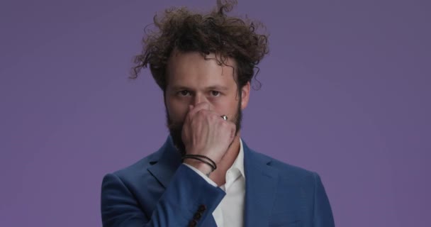 curly hair man holding breath and making funny faces, having fun, being crazy and moving mouth on purple background - Video, Çekim