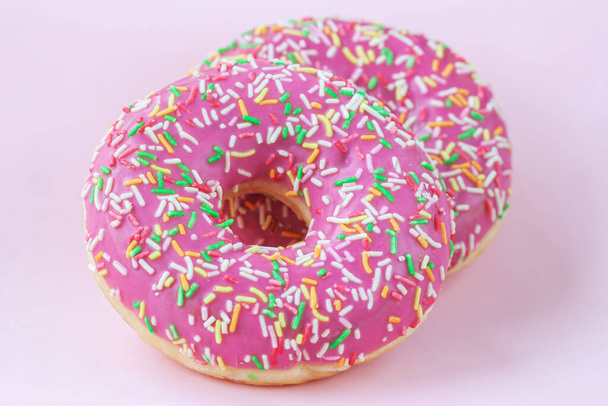 Two bright glazed donuts on pink background close-up - Foto, Imagem
