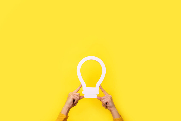 lampadina in mani su sfondo giallo - Foto, immagini