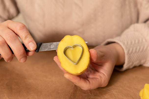 heart shaped potato stamp on craft paper. The process of decorating a gift for Valentines Day. Getting ready for the celebration on February 14th. - Foto, imagen