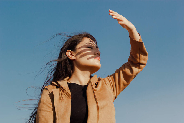 Kobieta zakrywa się dłonią przed słońcem. moda - Zdjęcie, obraz