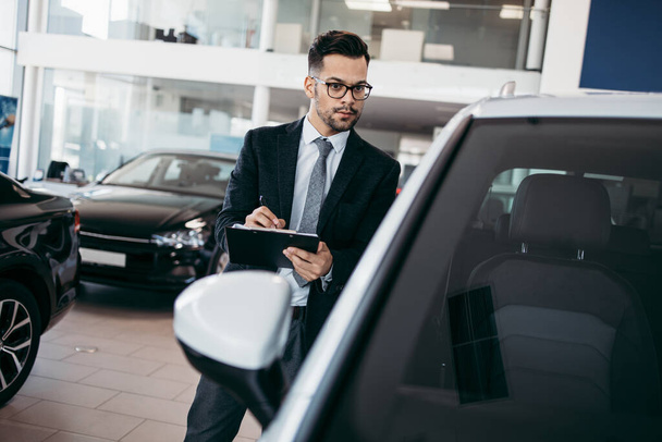 Car seller working in showroom and quality control checking of car details for the last time before buyer comes. - Φωτογραφία, εικόνα