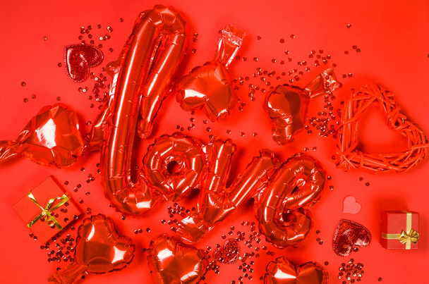 red Valentine love letter-shaped foil balloons and hearts foil balloons top view on red Valentines Day background. Copy Space. - Fotografie, Obrázek