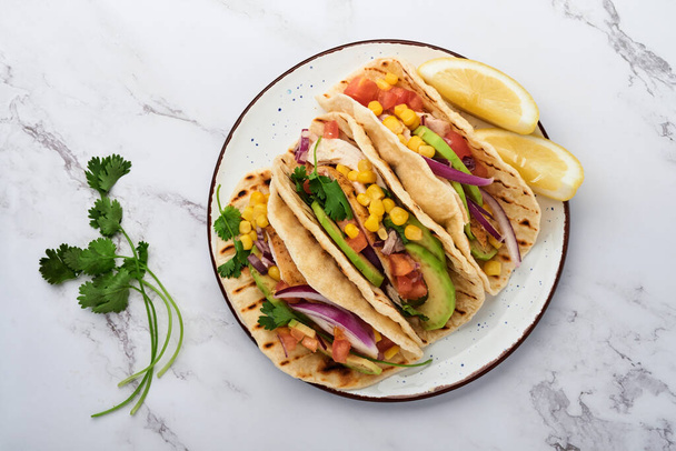 Mexican tacos with grilled chicken, avocado, corn kernels, tomato, onion, cilantro and salsa at white stone table. Traditional Mexican and Latin american street food. Top view. - Fotoğraf, Görsel