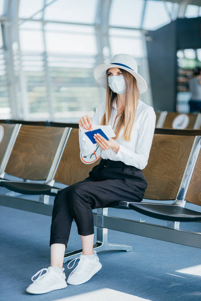 Beautiful business woman at the airport, using the phone to send text messages, standing by the window in the corporate office building, checking messages. The girl is holding tickets and a passport - Foto, Imagem