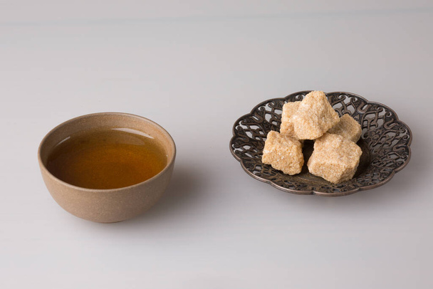 Traditional oriental cup with freshly brewed tea and pressed sugar on a saucer. - Foto, afbeelding