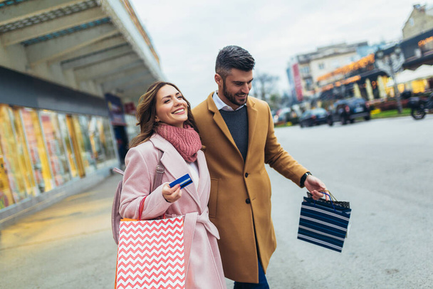 Joven pareja feliz después de comprar sosteniendo una tarjeta de crédito - Foto, imagen