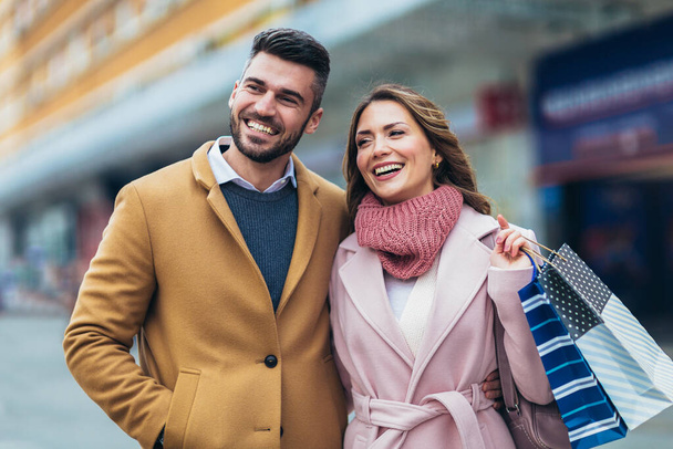 Lächelndes Paar spaziert nach dem Einkauf. - Foto, Bild