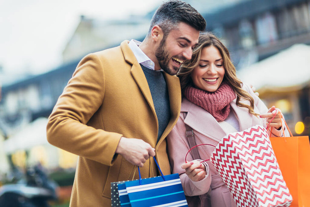 Usmívající se pár po nakupování a při pohledu do nákupních tašek. - Fotografie, Obrázek