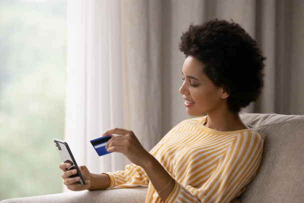Happy young African American woman shopping online. - 写真・画像