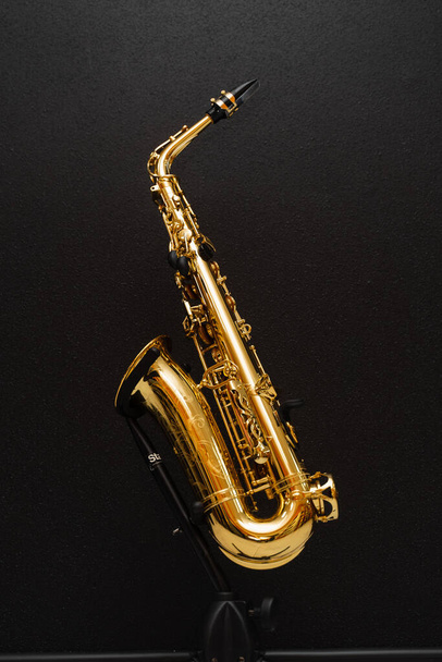 Saksofonowy instrument muzyczny do grania jazzu. Saksofon muzyk instrument na stoisku na czarnym tle - Zdjęcie, obraz