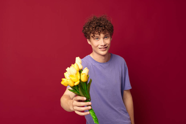 A young man holding a yellow bouquet of flowers purple t-shirts isolated background unaltered - Foto, immagini