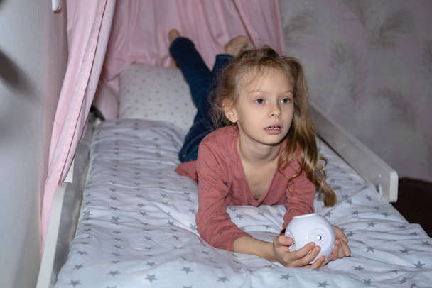 The girl has a small portable projector in her hands for watching movies - Zdjęcie, obraz