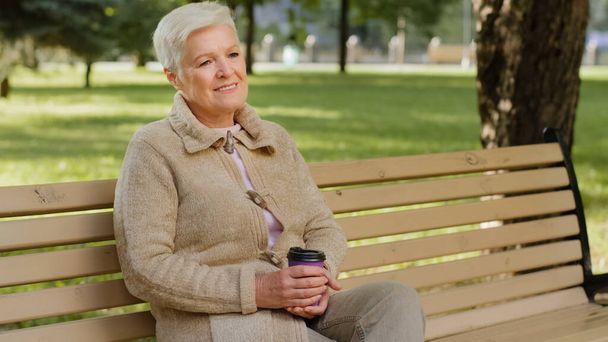 Wrinkled face of 60s happy elderly woman outdoors in park looking aside having wide smile, dental implants and prostheses satisfied client portrait, insurance for older people, natural beauty concept - Photo, Image