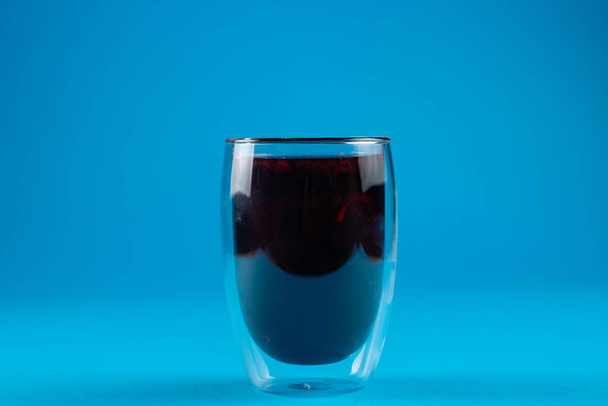 Τσάι Blueberry σε διπλό ποτήρι σε μπλε φόντο. - Φωτογραφία, εικόνα