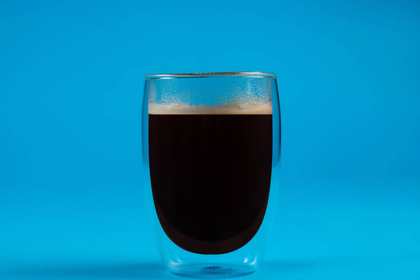 Café Americano sobre fondo azul. Espresso en taza de vidrio doble - Foto, Imagen
