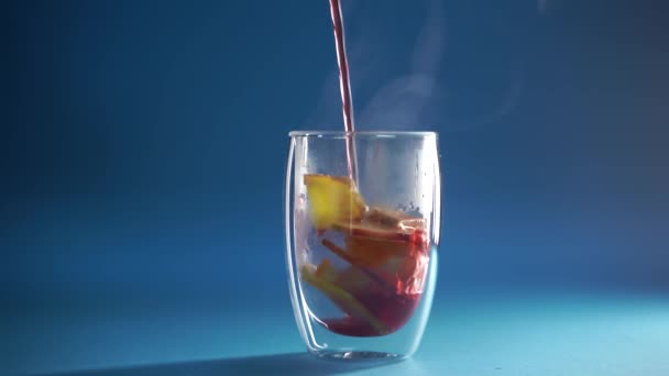 4k Video, das Glühwein in doppelter Glasschale auf blauem Hintergrund einschenkt. Alkoholpunsch Drink mit Orange, Anis, Zimt und Apfel. - Filmmaterial, Video