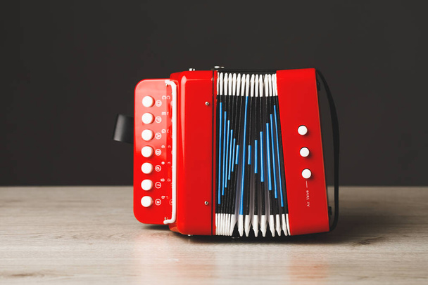 Gri arkaplanda kırmızı bayan oyuncak akordeonu - Fotoğraf, Görsel