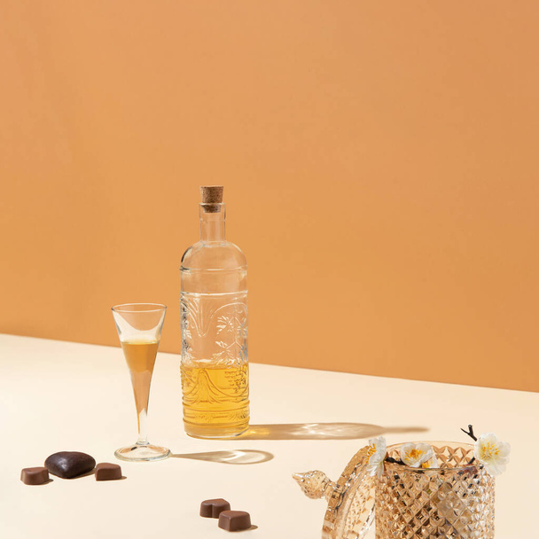 Bottiglia con tappo di sughero e vetro sul tavolo con pezzi di cioccolato a forma di cuore su fondo marrone - Foto, immagini