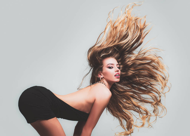Hair in motion. Face of the Beautiful young girl with long straight hair, posing in studio, gray isolated. Sensual woman look. - Photo, image