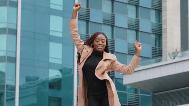 Boldog izgatott gyönyörű fiatal afro-amerikai üzletasszony tánc egyedül szabadtéri modern épület háttér ünneplik jutalom sikeres karrier vállalati promóció élvezze győzelem tánc koncepció - Felvétel, videó