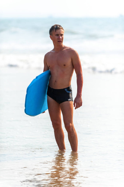 Young man with a board on the seashore. - Foto, afbeelding