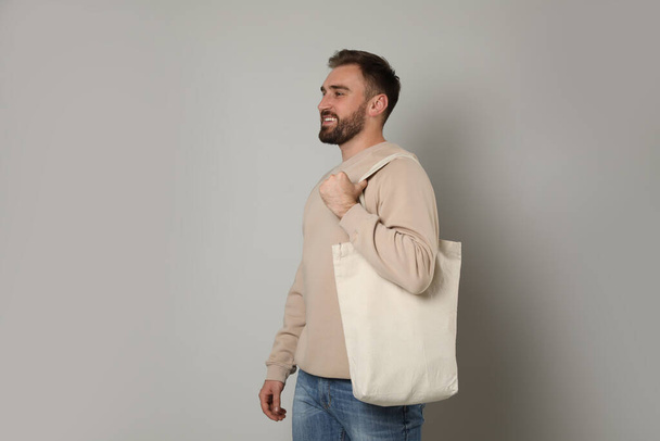 Happy young man with eco bag on light background - Foto, Imagem