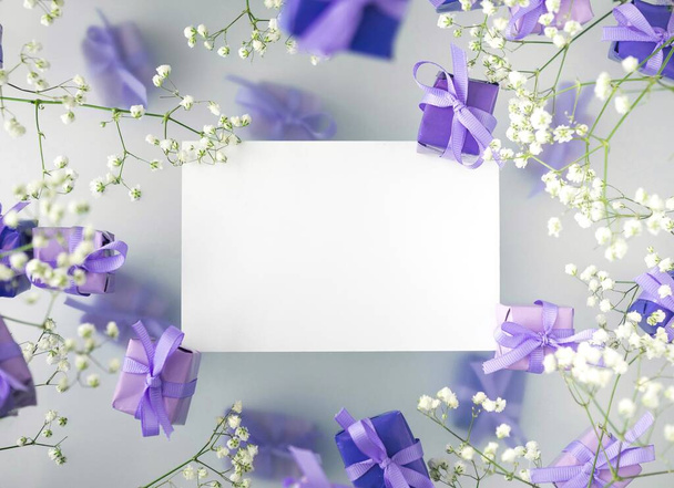 A multi-layered postcard made of gift boxes in a fashionable, trendy very peri color with white flowers on a foggy background. Happy women day and Valentines Day greeting card concept - Photo, Image