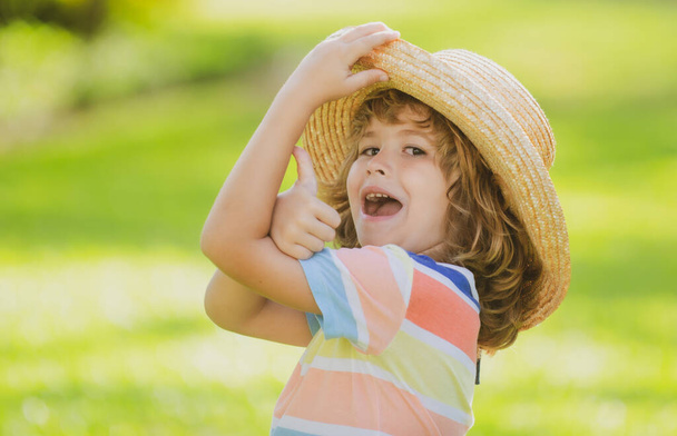 Portrait of a happy laughing child in summer nature park with thumbs up sign. Positive kids in straw hat. Summer vacation. - Photo, Image