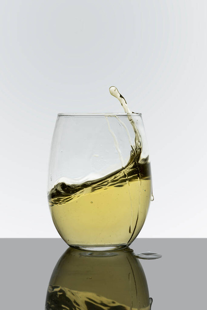 Glass cup with drink in motion with a white background - Fotó, kép