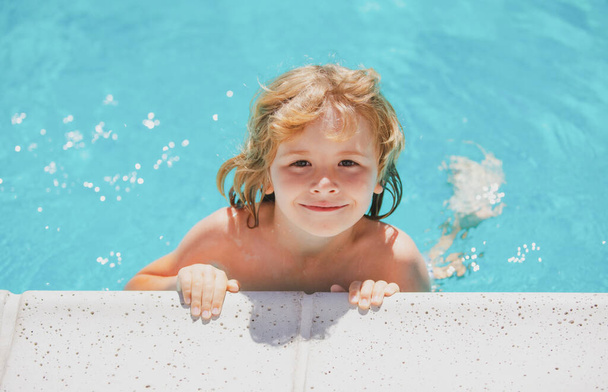 Cute child boy swim in swimming pool, summer water background with copy space. Funny kids face. Kid playing outdoors. Summer vacation and healthy lifestyle concept. - 写真・画像